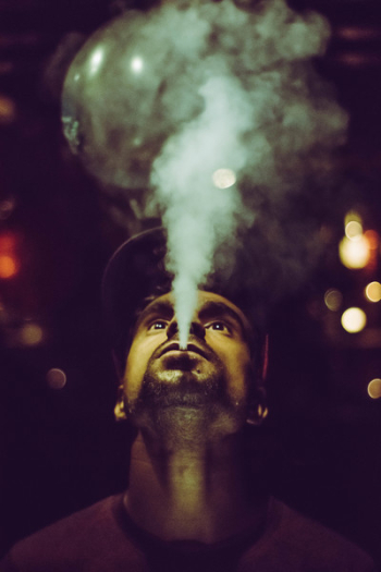 Man Wearing Crew-neck Shirt and Fitted Cap Smoking