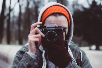 Man Wearing Gray Hooded Jacket Holding Black Camera