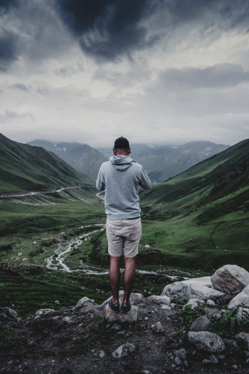 Man Wearing Grey Hooded Jacket Standing on the Cliff Man Wearing Grey Hooded Jacket Standing on the Cliff
