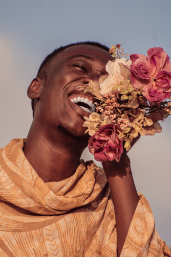 Man Wearing Orange Top Holding Flowers While Laughing Man Wearing Orange Top Holding Flowers While Laughing