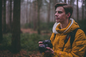 man wearing yellow parka jacket holding DSLR camera man wearing yellow parka jacket holding DSLR camera