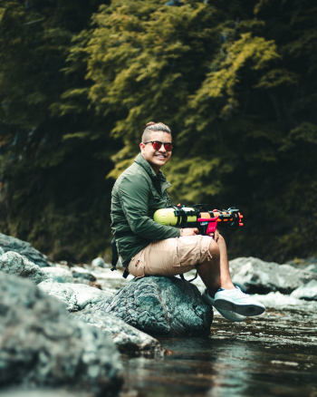 Man With A Toy Gun Sitting on A Rock Boulder Man With A Toy Gun Sitting on A Rock Boulder