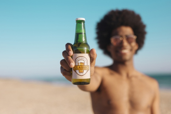 Man with beer bottle mockup at the beach Free Psd