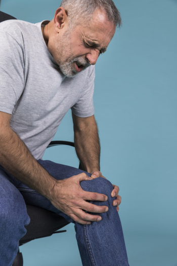 Man with knee pain sitting on chair Man with knee pain sitting on chair