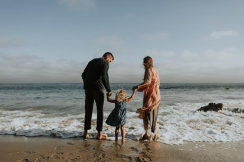 man, woman and child standing on seashore during daytime