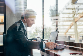 Mature businessman working on laptop in bar Mature businessman working on laptop in bar
