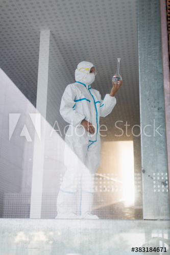 Medical scientist examining beaker in science laboratory Medical scientist examining beaker in science laboratory