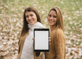 Medium shot two smiling women holding tablet in hands Free Photo