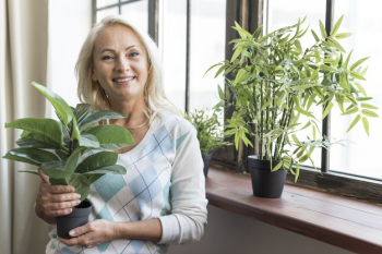 Medium shot woman holding a plant Free Photo Medium shot woman holding a plant Free Photo