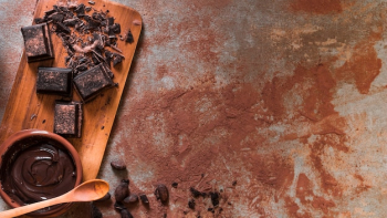 Melted chocolate bowl and crushed bar on chopping board with wooden spoon
