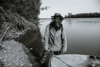 Middle aged Asian male standing near boat in lake before fishing