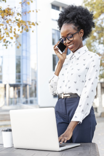 Modern woman working on laptop and talking over phone Free Photo