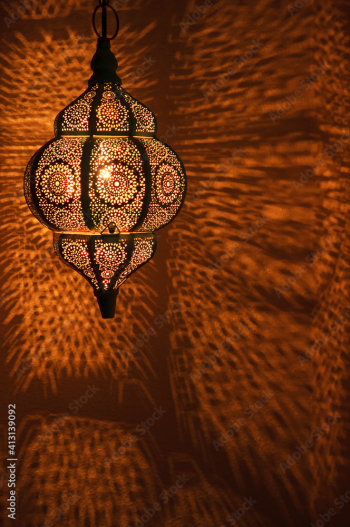 Moroccan golden lamp with circular patterns of light on wall for bohemian theme.