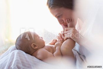 Mother kissing feet of baby son