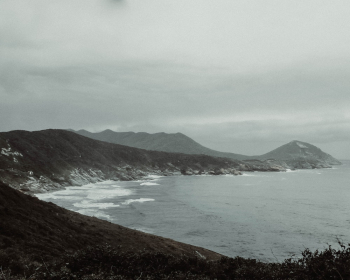 Mountain Overlooking Beach Under Grey Cloudy Sky Mountain Overlooking Beach Under Grey Cloudy Sky