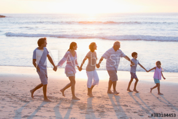 Multi-generation family holding hands and walking on sunny beach Multi-generation family holding hands and walking on sunny beach