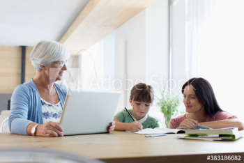 Multi-generation family using laptop and coloring at dining table Multi-generation family using laptop and coloring at dining table