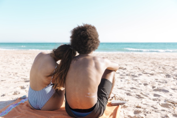 Multiethnic couple sitting on beach Free Photo Multiethnic couple sitting on beach Free Photo