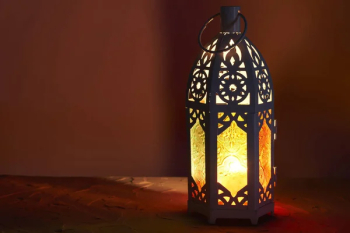 Ornamental Arabic lantern with burning candle glowing in dark. Festive greeting card, invitation for Muslim holy month Ramadan Kareem