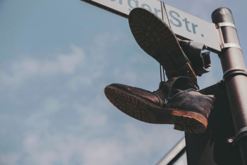 pair of black boots hanged on street post pair of black boots hanged on street post