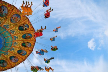 people riding carnival ride under blue skies people riding carnival ride under blue skies