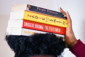 person carrying four assorted-title books on head