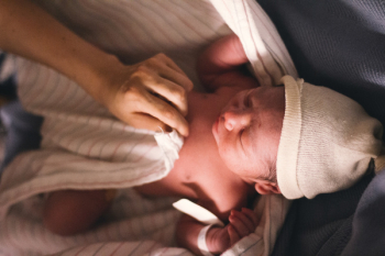 Person Covering Infant With Swaddling Blanket Person Covering Infant With Swaddling Blanket