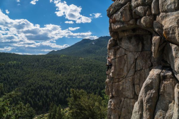 person doing rock climbing under white clouds at daytime person doing rock climbing under white clouds at daytime