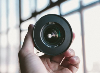 person holding black Nikon camera lens person holding black Nikon camera lens