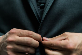person holding black suit jacket button person holding black suit jacket button