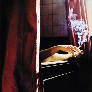 person holding cigarette near window person holding cigarette near window