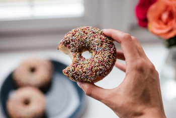 Person Holding Doughnut With Sprinkles Person Holding Doughnut With Sprinkles