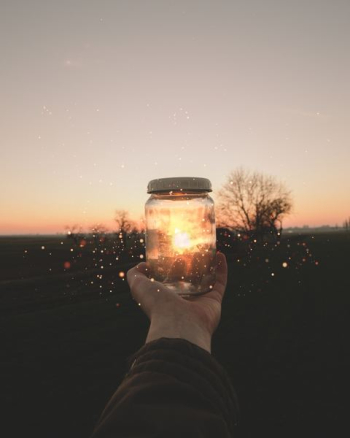 person holding glass jar person holding glass jar