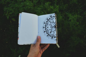 Person Holding Open Book with Floral Drawing Person Holding Open Book with Floral Drawing