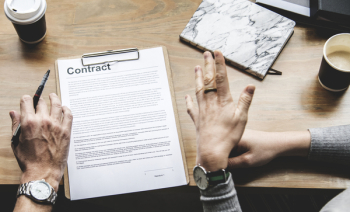 Person Holding Pen in Front Of Contract Person Holding Pen in Front Of Contract