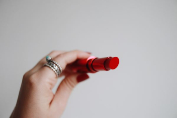 person holding red lipstick person holding red lipstick