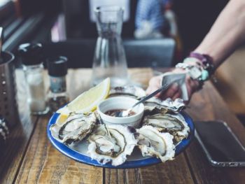 person holding round blue plate with seafood and sauce in white ceramic bowl