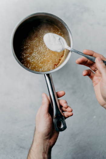 Person Holding Stainless Pan With Brown Liquid Person Holding Stainless Pan With Brown Liquid