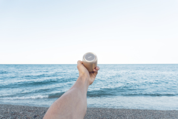 Person Holding Upward Brown Speaker in Front of Sea