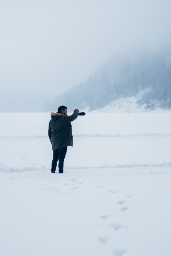 Person In Black Parka Hoodie Standing On Snow Covered Road Person In Black Parka Hoodie Standing On Snow Covered Road