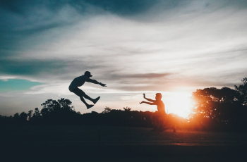 Person in Front of Man Flying Wearing Hat during Sunset Person in Front of Man Flying Wearing Hat during Sunset