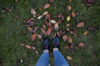 Person in Patent Black Low-top Shoes Standing Above Green Grass