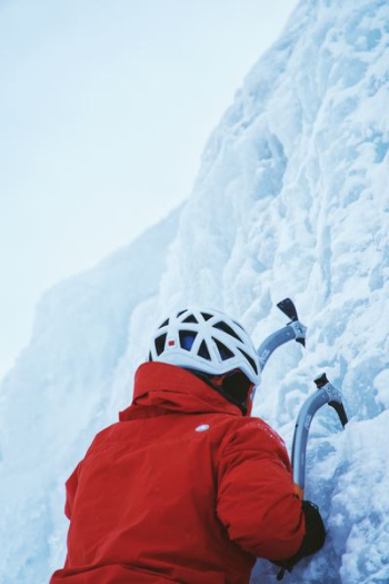 person in red jacket while climbing ice wall at daytime person in red jacket while climbing ice wall at daytime