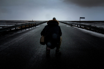 Person Kneeling on Concrete Pavement Wearing Parka Jacket