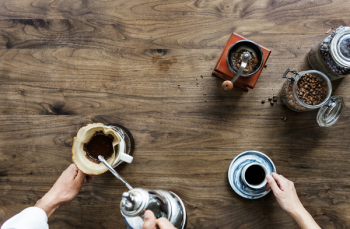 Person Making Coffee Beside Person Holding Cup of Coffee