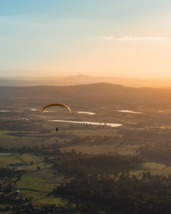 person paragliding above countryside during daytime person paragliding above countryside during daytime