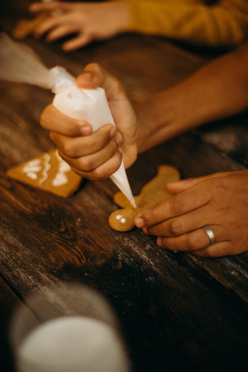 Person Piping Icing on Gingerbread Cookie Person Piping Icing on Gingerbread Cookie