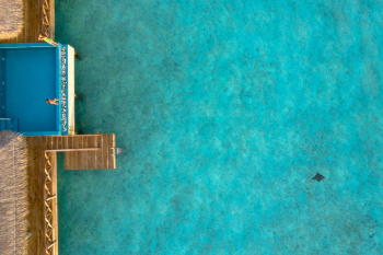 Person Sitting on Infinity Pool With Beach in Front