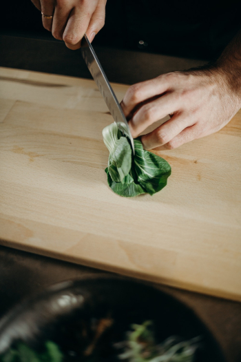 Person Slicing Green Leafy Vegetable Person Slicing Green Leafy Vegetable