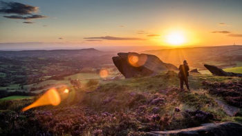 person standing near rock formation during sunset person standing near rock formation during sunset